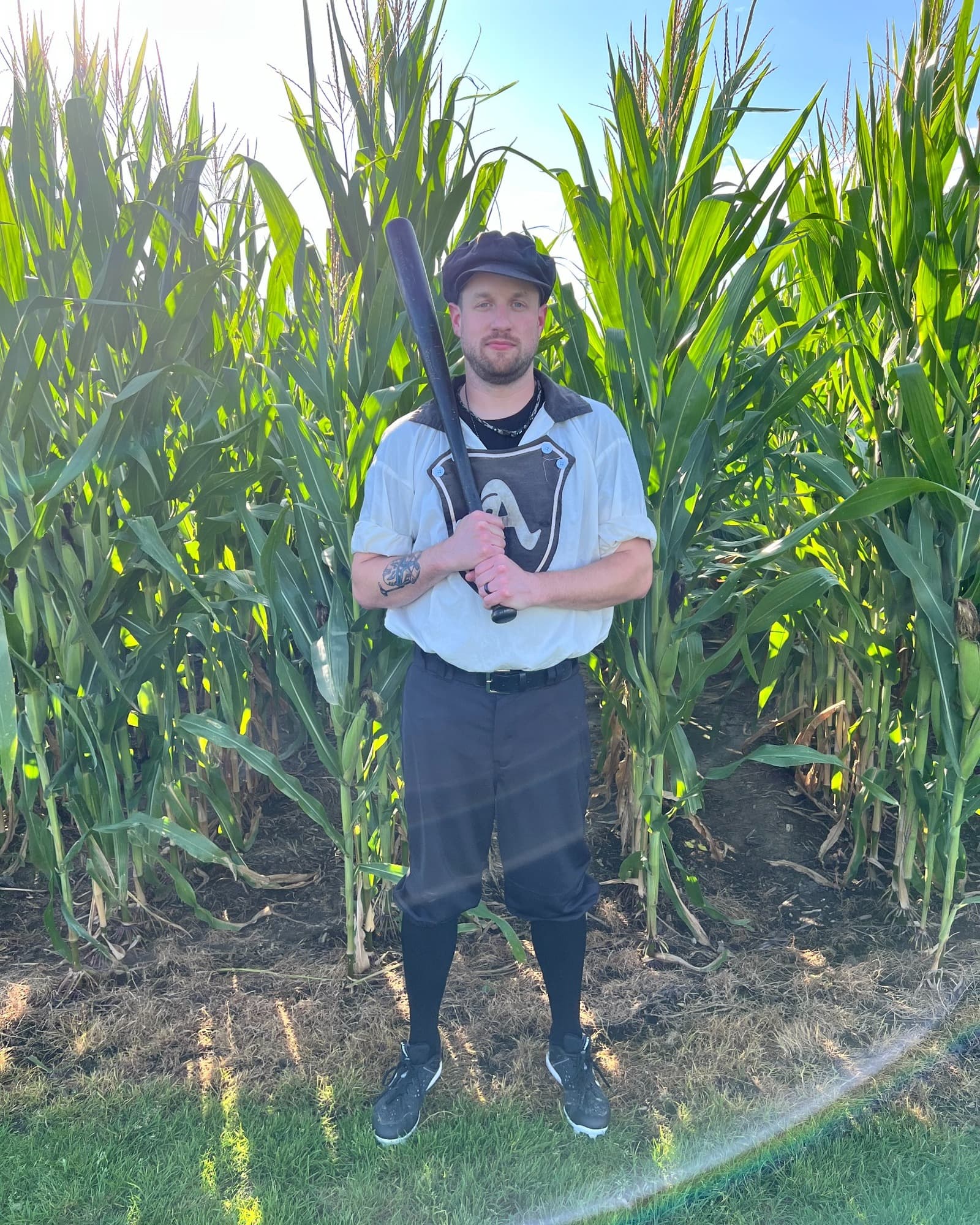 Eric with a bat standing in a cornfield